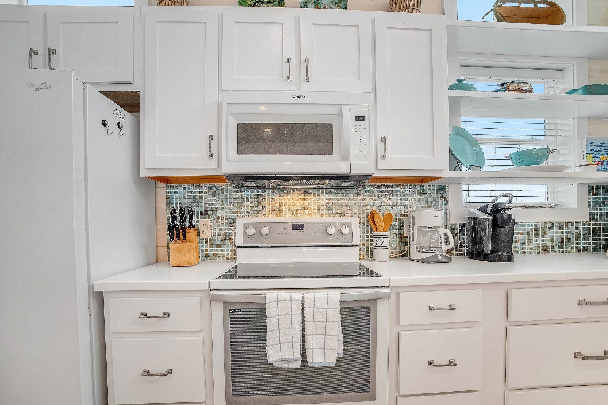 A kitchen with white cabinets, a microwave, an oven, and a coffee maker.