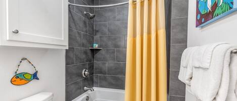 Une salle de bain avec une baignoire, des toilettes et un rideau de douche.