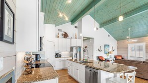 A modern kitchen with white cabinets, a granite countertop, and a dishwasher. - Eleventh III (Port Aransas)