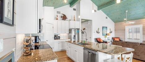 A modern kitchen with white cabinets, a granite countertop, and a dishwasher.