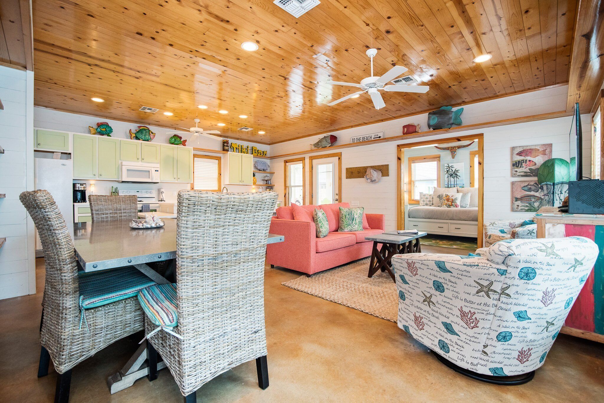 A cozy living area with wicker furniture, a pink sofa, and a ceiling fan.