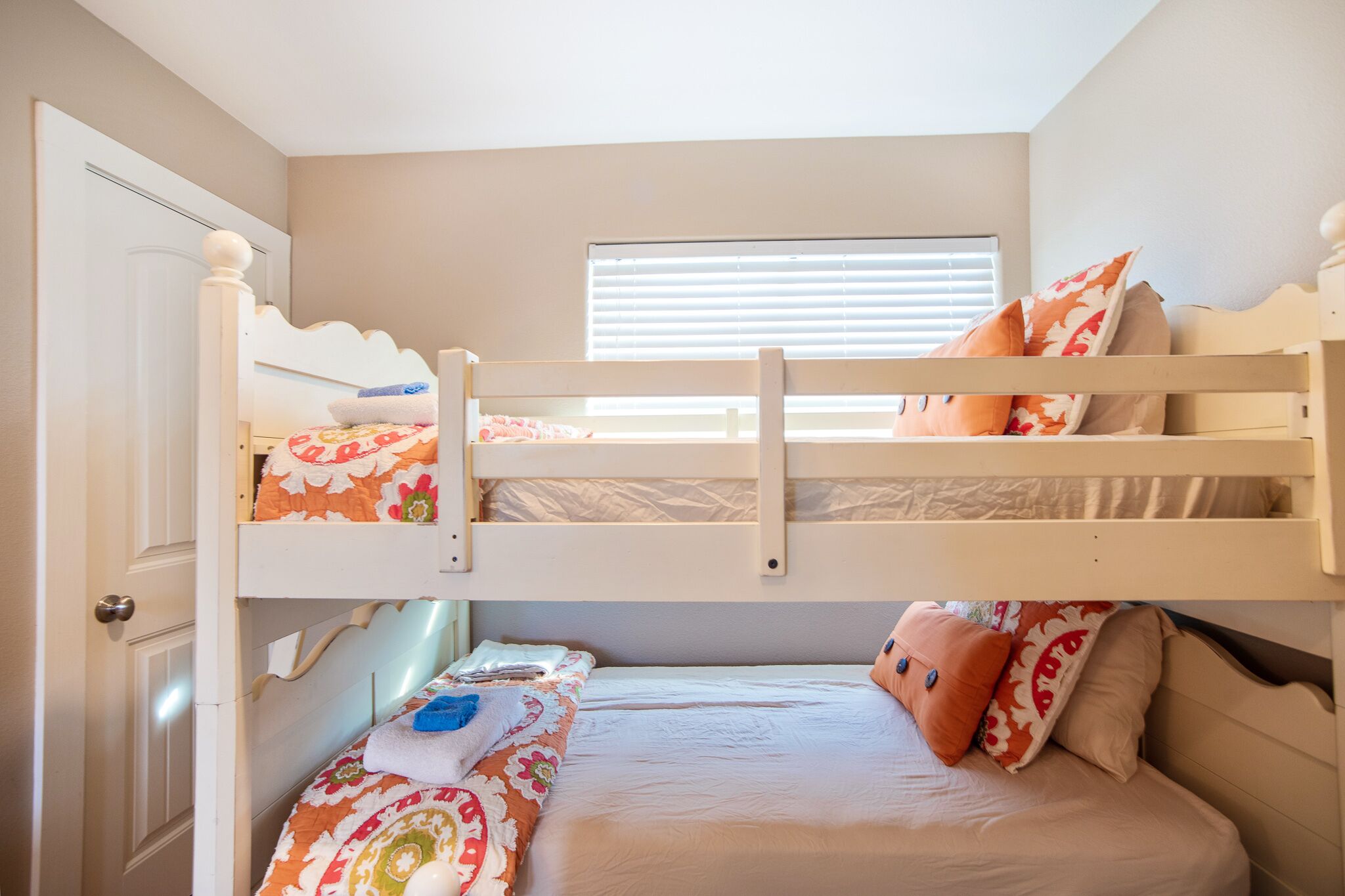 A bunk bed room with a window, a door, and a bed with pillows.