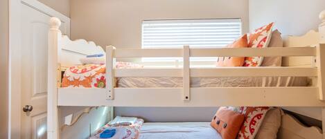 A bunk bed room with a window, a door, and a bed with pillows.
