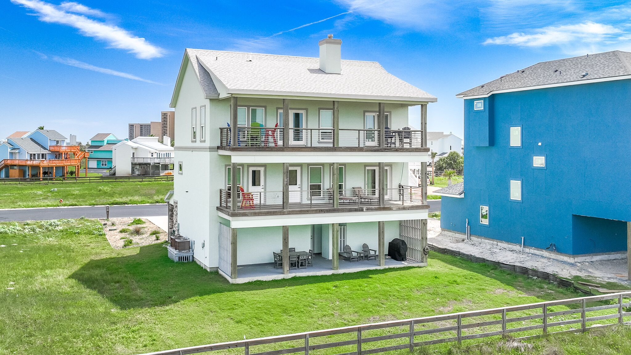 A multi-story building with balconies, a covered patio, and a blue building adjacent to it.