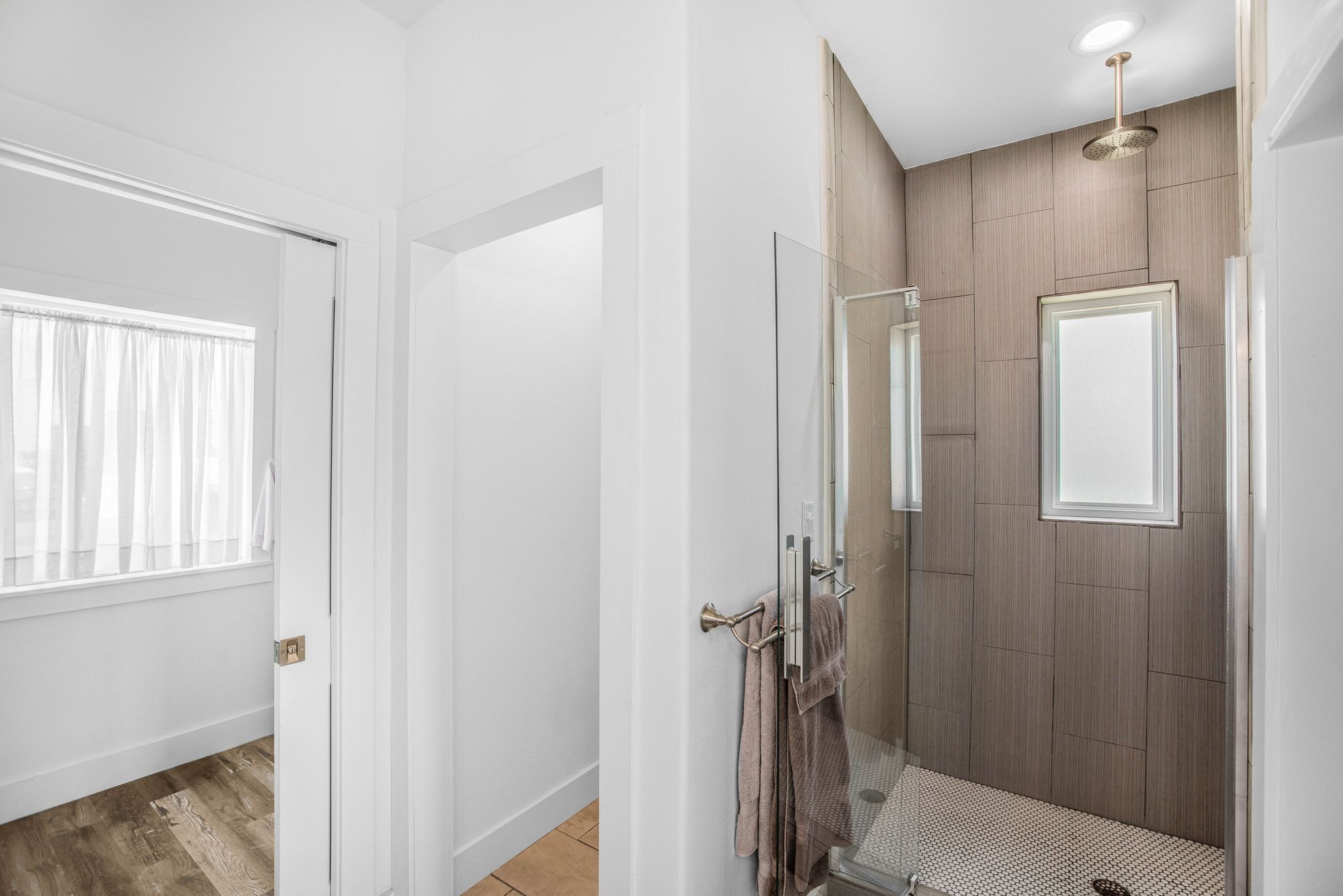 Un baño moderno con ducha, puerta de cristal y panel de pared de madera.