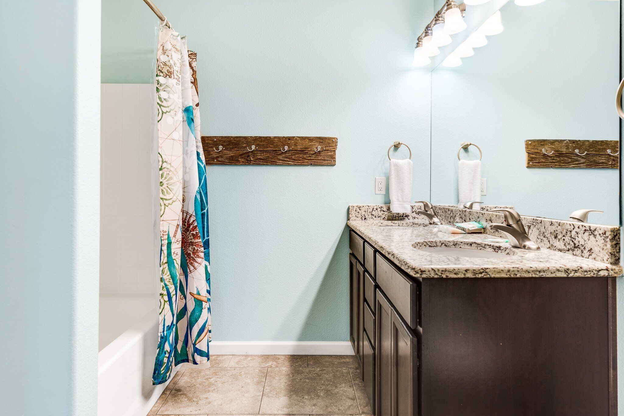 Une salle de bain avec un rideau de douche, un lavabo avec un robinet et un miroir.