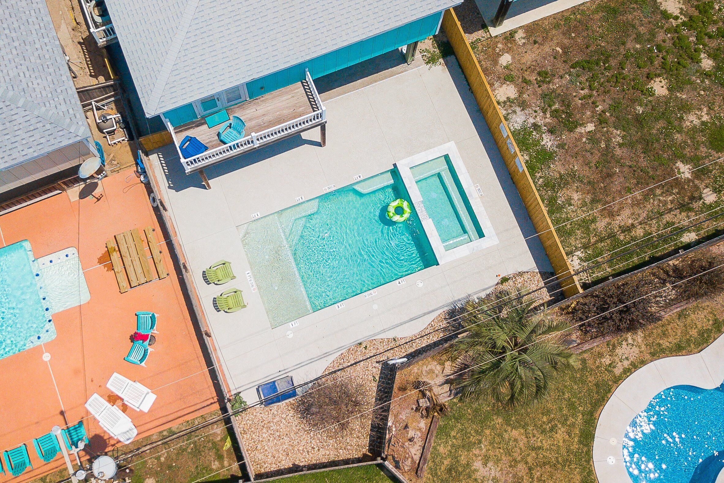Eine Vogelperspektive zeigt einen Garten mit Swimmingpool, Liegestühlen und einer Holzterrasse.