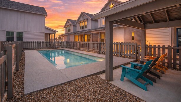 Un quartier résidentiel doté d’une piscine, d’une terrasse en bois et de maisons avec garage attenant.