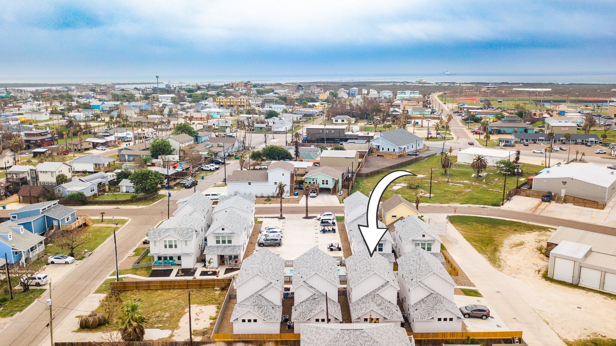 A residential area with detached houses, a main road, and a large building with a curved roof.