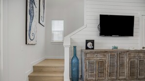 Un escalier avec des finitions en bois, un vase bleu et un meuble rustique doté de volets.