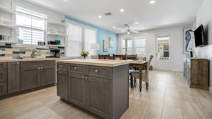 Une cuisine moderne avec des meubles de couleur sombre, un îlot central et un coin repas comprenant une table et des chaises.
