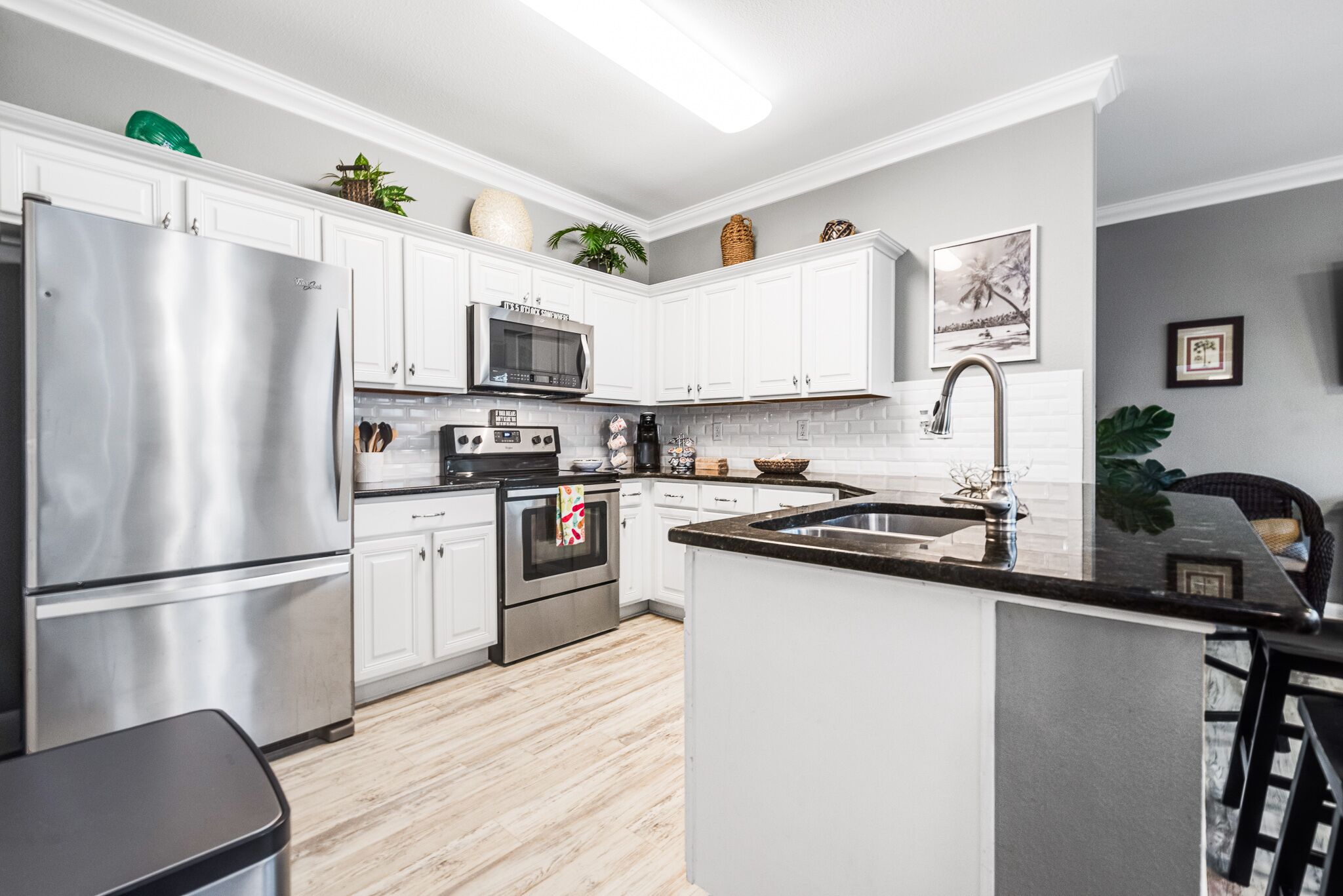 A modern kitchen with white cabinets, stainless steel appliances, and a central island with a sink.