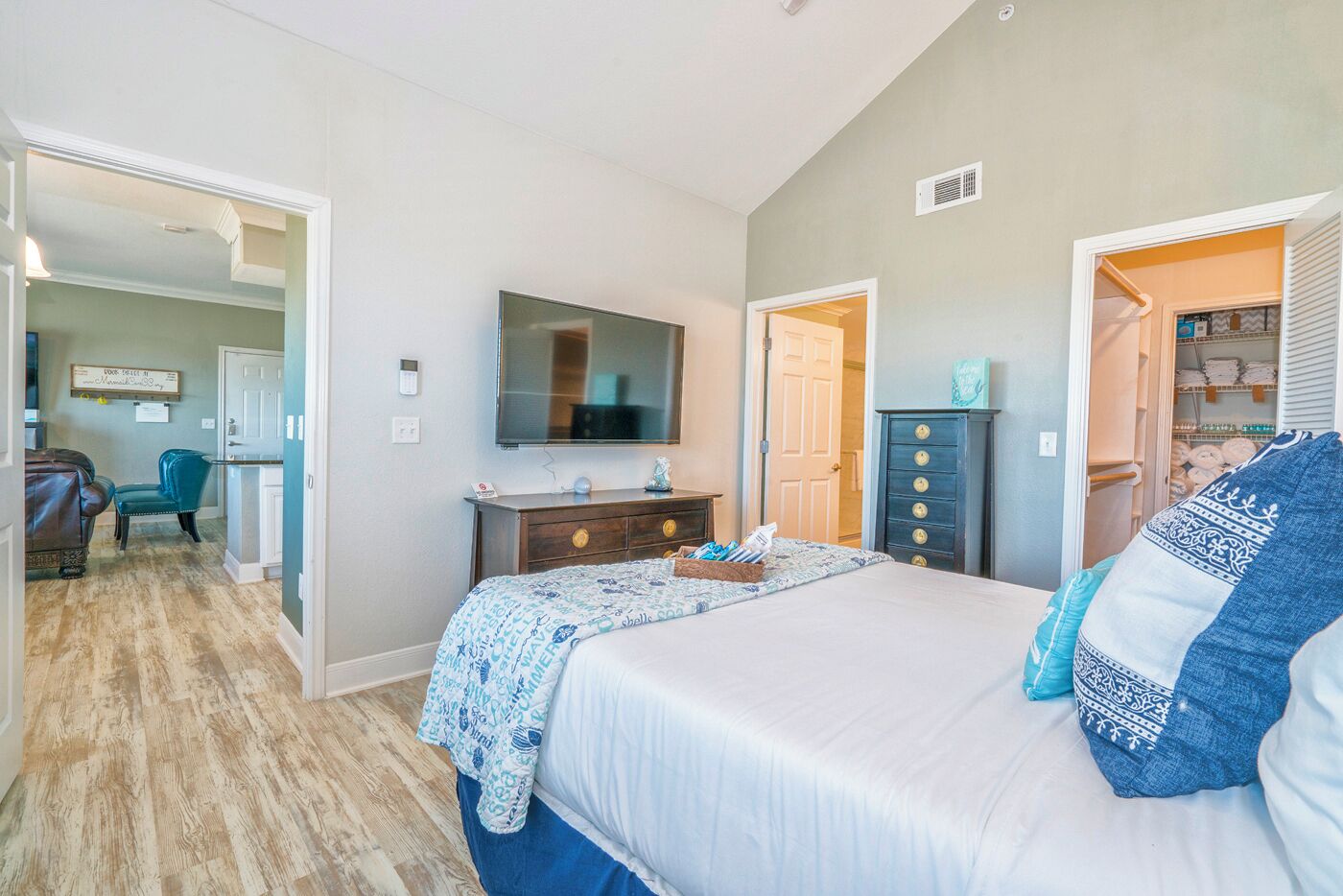 A bedroom with a bed, a dresser, a television, and a closet.