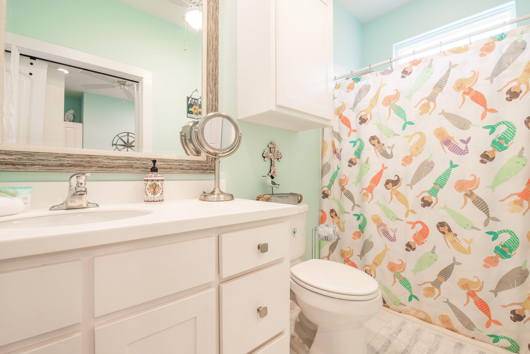A bathroom with a white vanity, a round mirror, and a toilet.