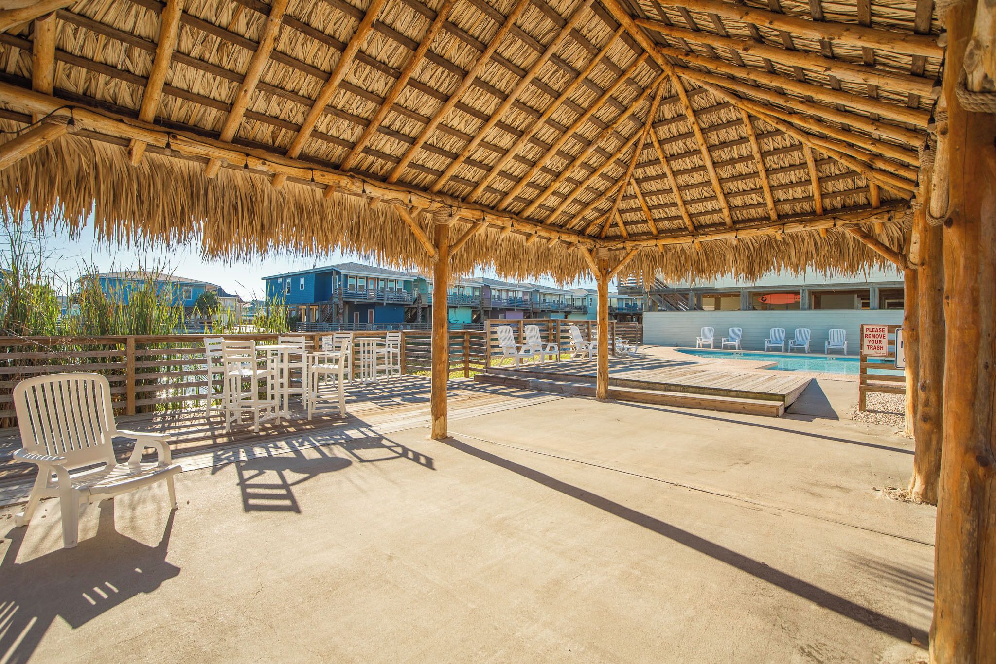 Ein überdachter Außenbereich mit Pool, Liegestühlen und einer Holzterrasse.