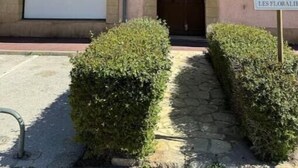 Un edificio con una fachada cerrada, un letrero de no estacionamiento y un acceso con portón.