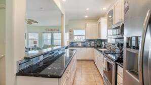 A modern kitchen with white cabinets, stainless steel appliances, and a black granite countertop. - Turquoise Treasure - Boardwalk to the Beach! Beach Gear Credit I (Port Aransas)
