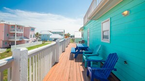 A turquoise building with a wooden deck, blue chairs, and a picnic table. - Turquoise Treasure - Boardwalk to the Beach! Beach Gear Credit I (Port Aransas)