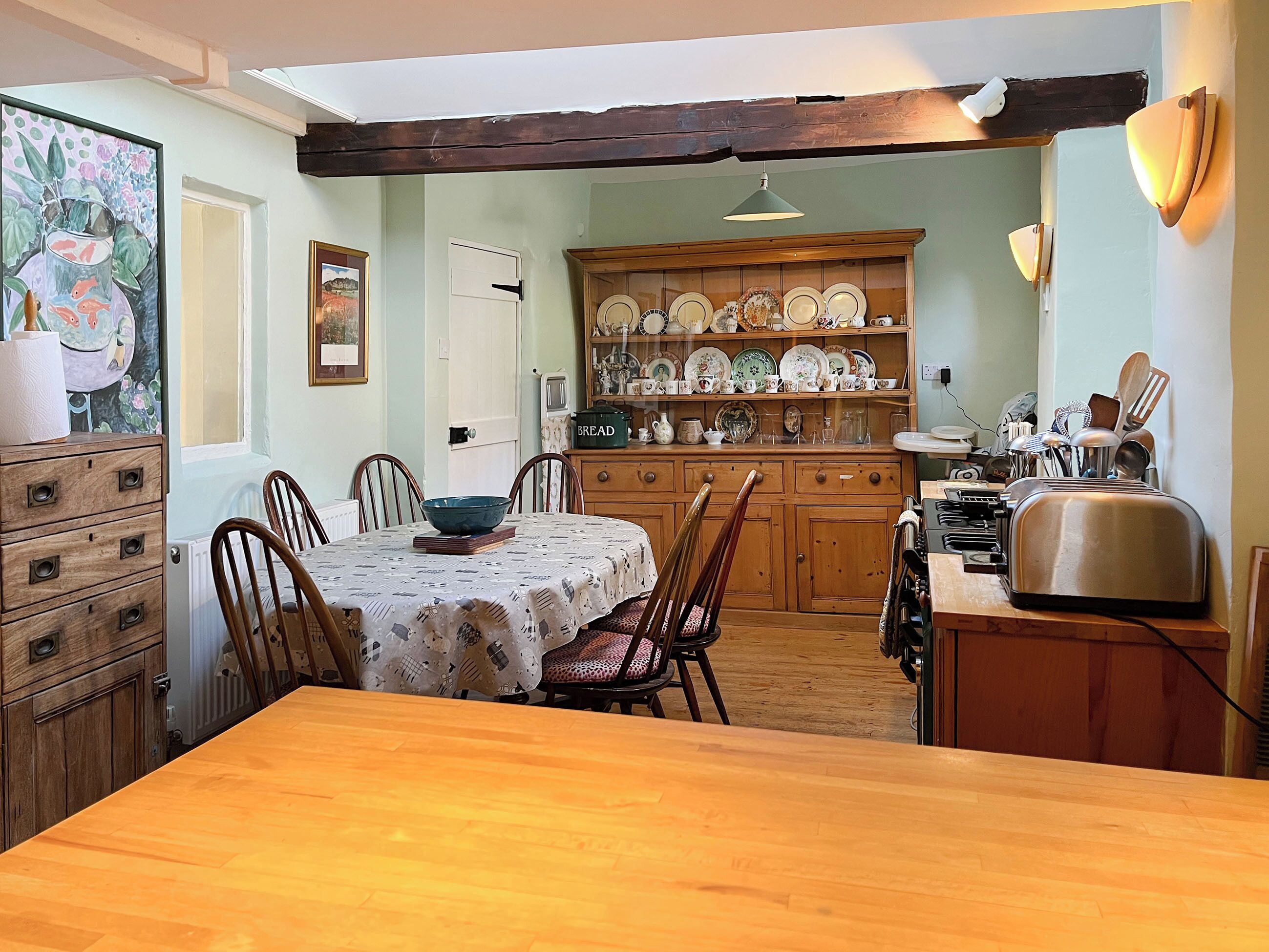 A dining area with a wooden table, chairs, and a cabinet with dishes.