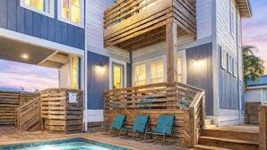 Ein mehrstöckiges Haus mit Pool, Holzterrasse und Sitzgelegenheit im Freien.