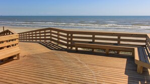 A wooden boardwalk leading to a beach with a wooden bench and railing. - Casa Las Palmas - Pet Friendly! Boardwalk to the Beach! (Port Aransas)