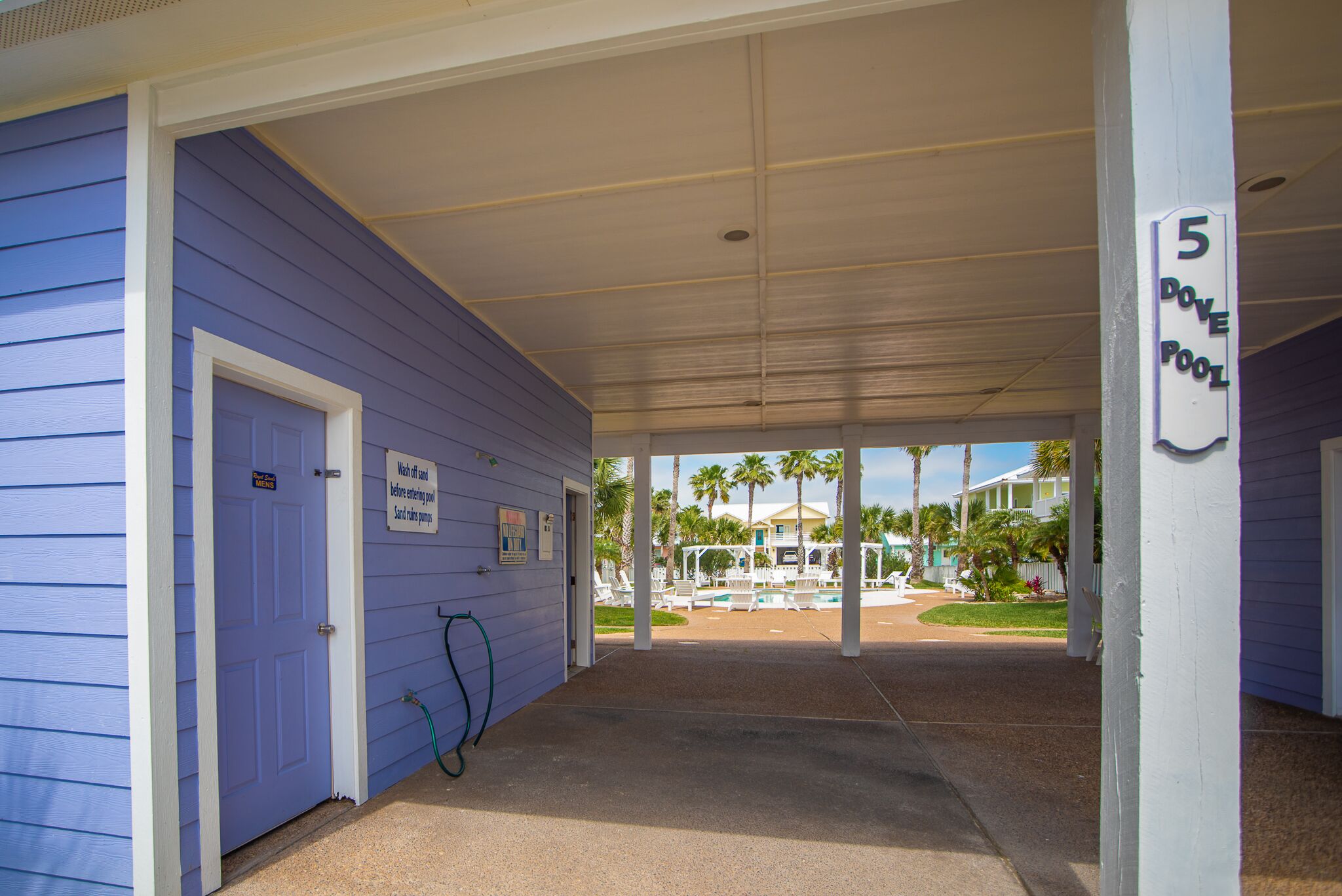 A covered outdoor area with a pool, a door, and a sign indicating '5 DOVE POOL'.