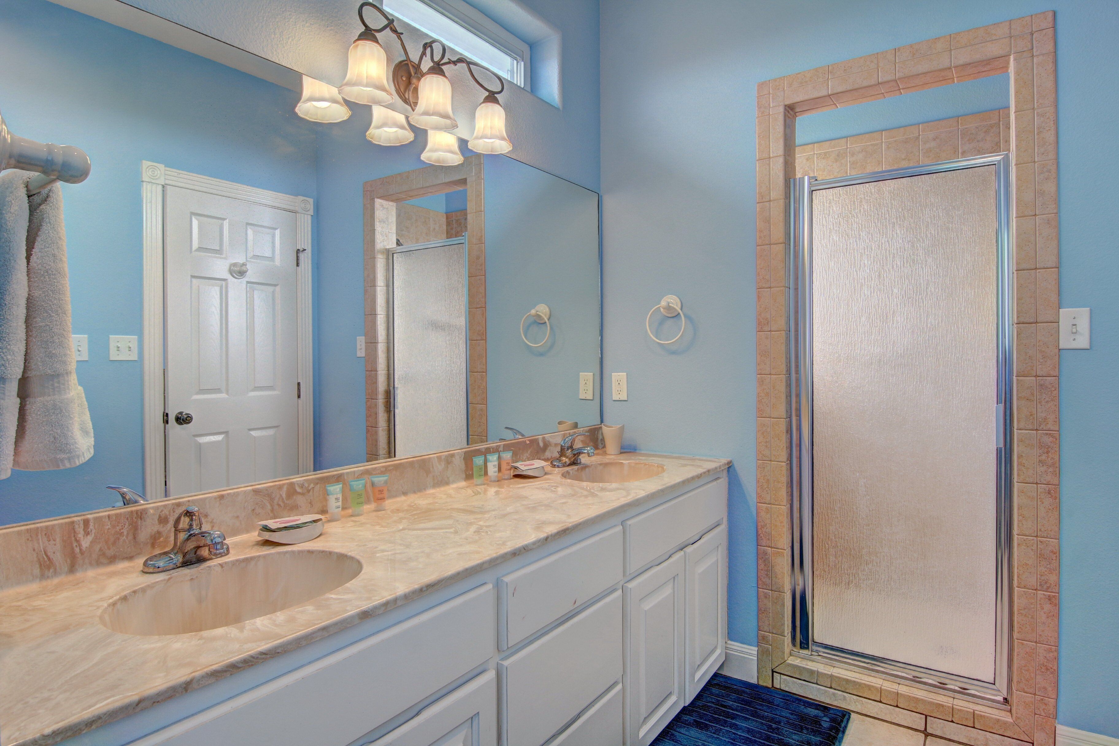 A bathroom with two sinks, a large mirror, and a shower enclosure.