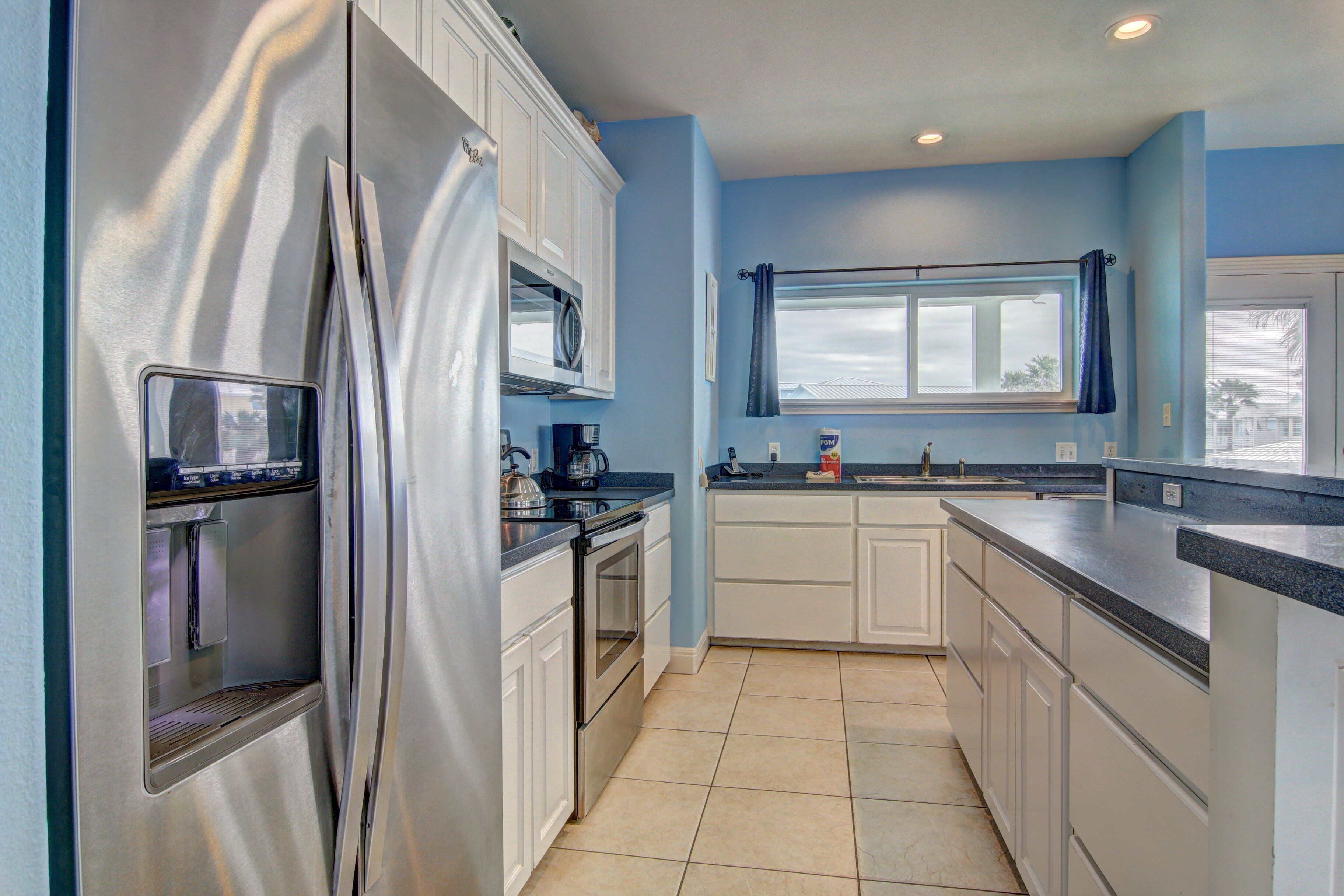 A modern kitchen with stainless steel appliances, white cabinetry, and a blue accent wall.