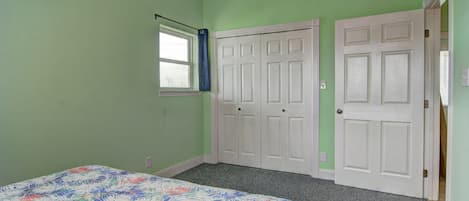 A bedroom with a bed, a window with a curtain, and a door.