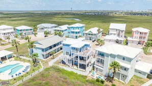 A coastal residential area with multiple two-story houses, a swimming pool, and a clear view of the beach and ocean. - Casa Azul - Boardwalk to the Beach! (Port Aransas)