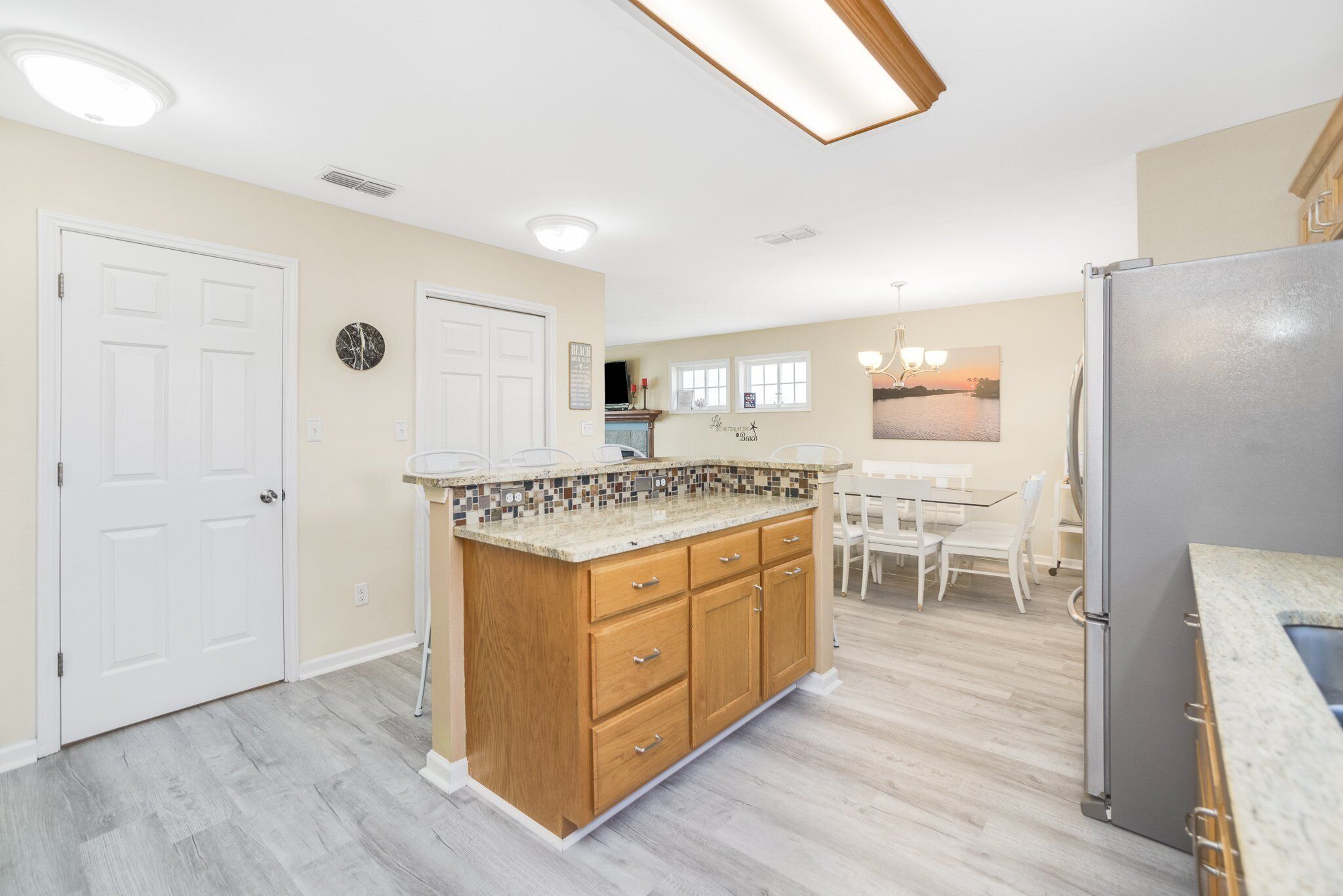 A kitchen with a wooden island, white cabinets, and a stainless steel refrigerator.