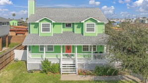 A two-story house with a green exterior and a white porch. - Palma Verde - Pet Friendly! (Port Aransas)