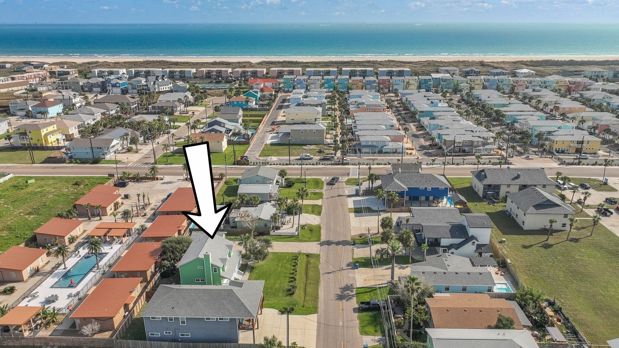 A coastal residential area with houses, a swimming pool, and a view of the ocean.