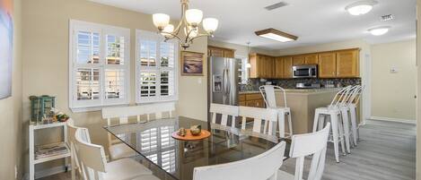 A spacious kitchen with a central island, white cabinetry, and a modern chandelier.