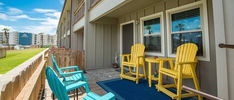 A patio with outdoor seating, a wooden fence, and a view of a hotel building in the background.