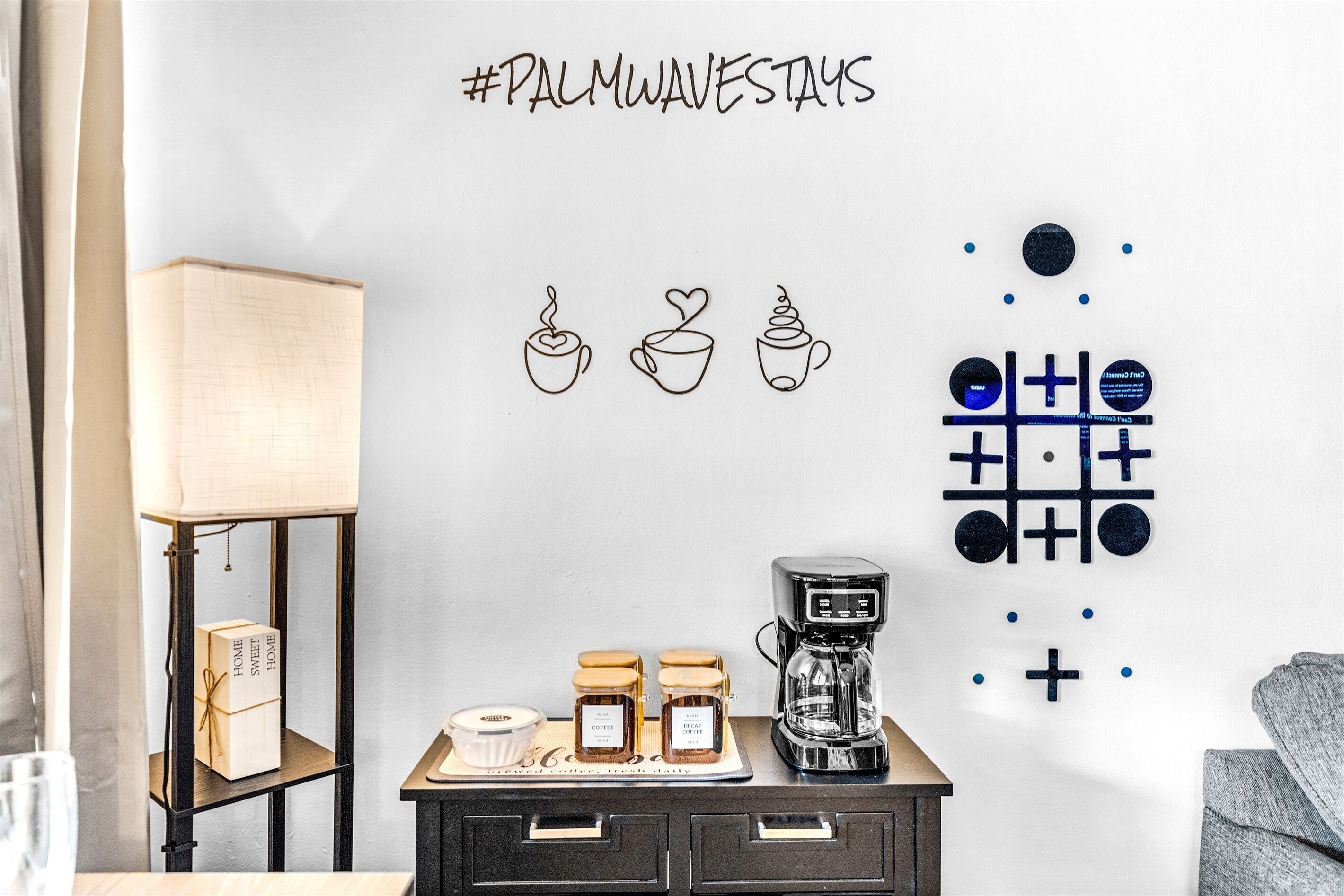 A wall with a coffee station, a lamp, and wall art.