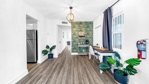 A modern kitchen with a stainless steel refrigerator, a coffee bar, and a dining area with a table and chairs. - Stocked Condo - Sleeps 10 - Palmwavestays (Coconut Creek)