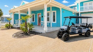 A coastal building with a porch, a golf cart, and palm trees.