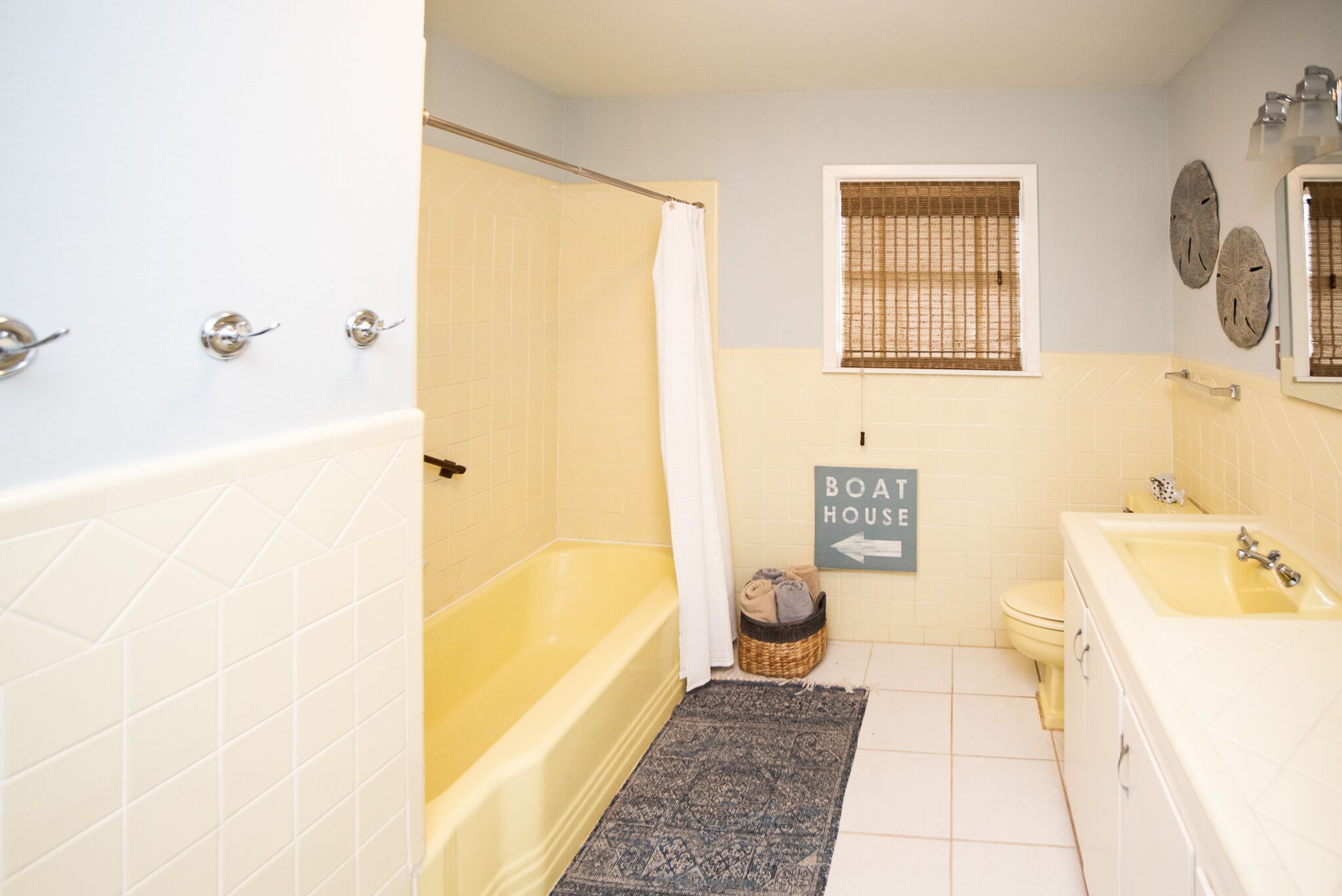 A bathroom with a bathtub, toilet, and sink. There is a sign indicating the direction to the boat house.