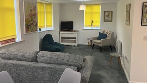 A living room with a grey sofa, a bean bag, a TV on a stand, and a small table. - Sleeps 4 With Ensuite and Free Parking (Lincoln)