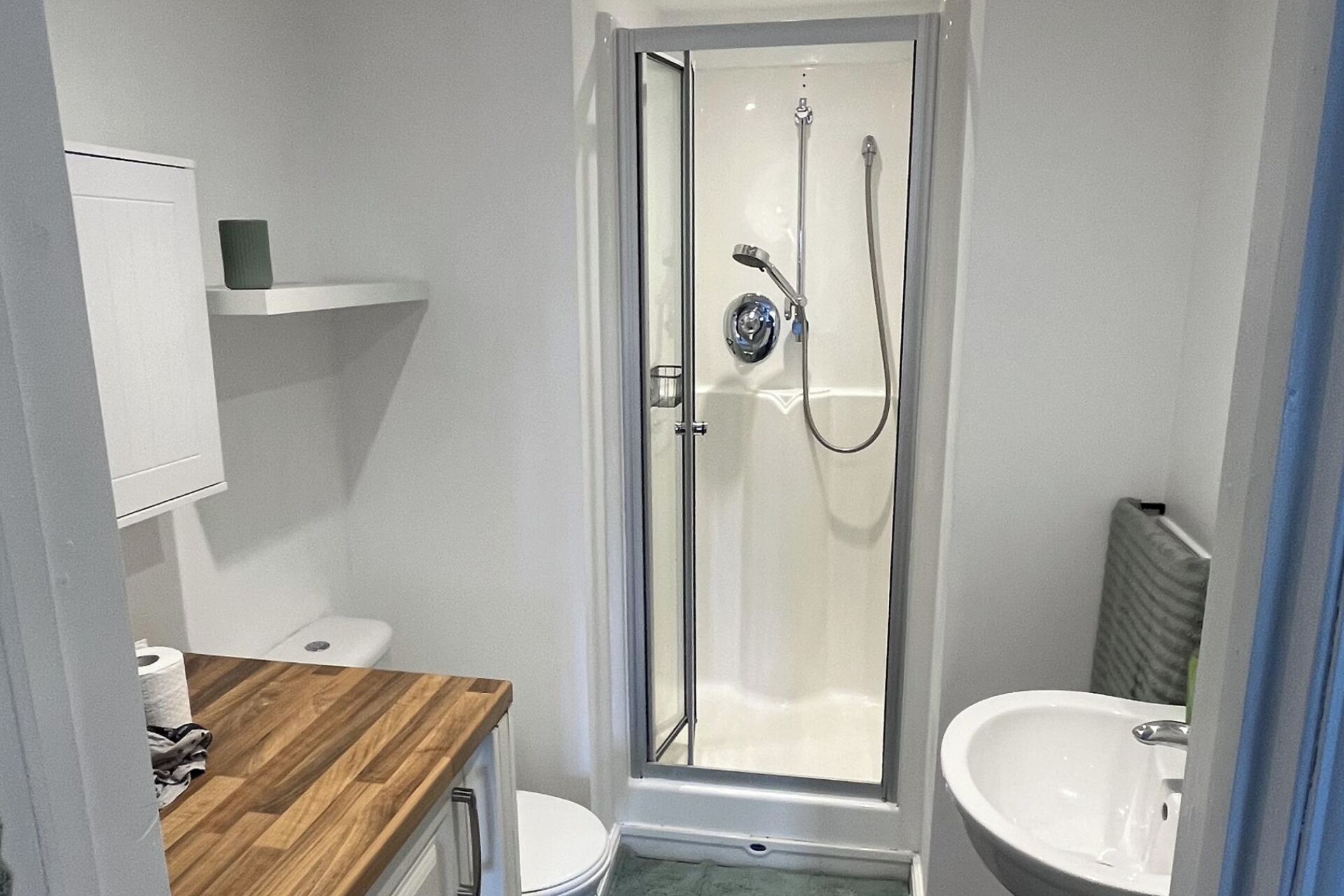 Et badeværelse med bruser, toilet og håndvask.