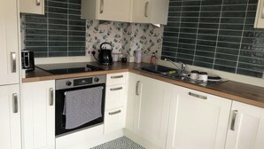 A compact kitchen with white cabinets, a black oven, a stainless steel sink, and a patterned backsplash. - Sleeps 4 With Ensuite and Free Parking (Lincoln)