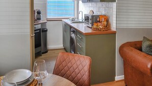 Eine kompakte Küche mit integriertem Waschmaschine, Toaster und einer kleinen Essecke mit Tisch und Stühlen.