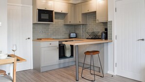 Une cuisine de taille réduite, avec des meubles blancs, un four à micro-ondes, un grille-pain et un évier.