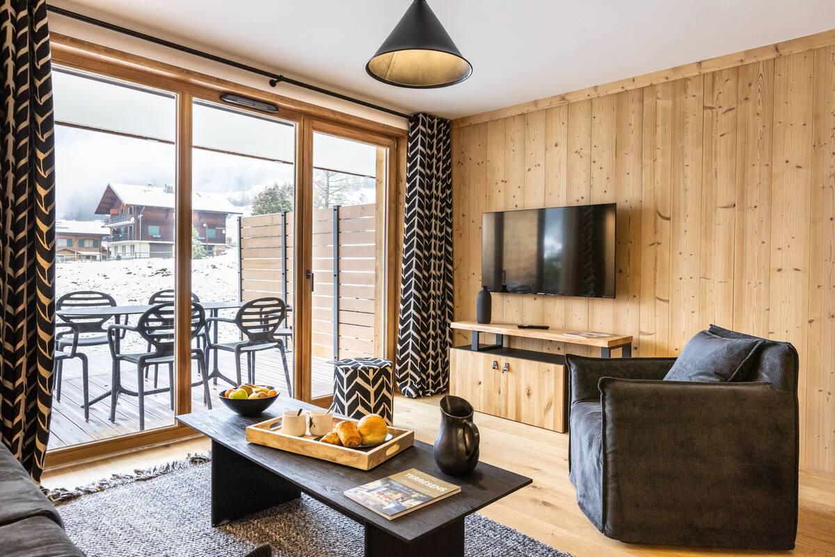 Ein modernes Wohnzimmer mit einer Couch, einem Couchtisch und einem Fernseher.