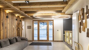 Un intérieur moderne avec un plafond en bois, un canapé gris et une vue à travers des portes vitrées.