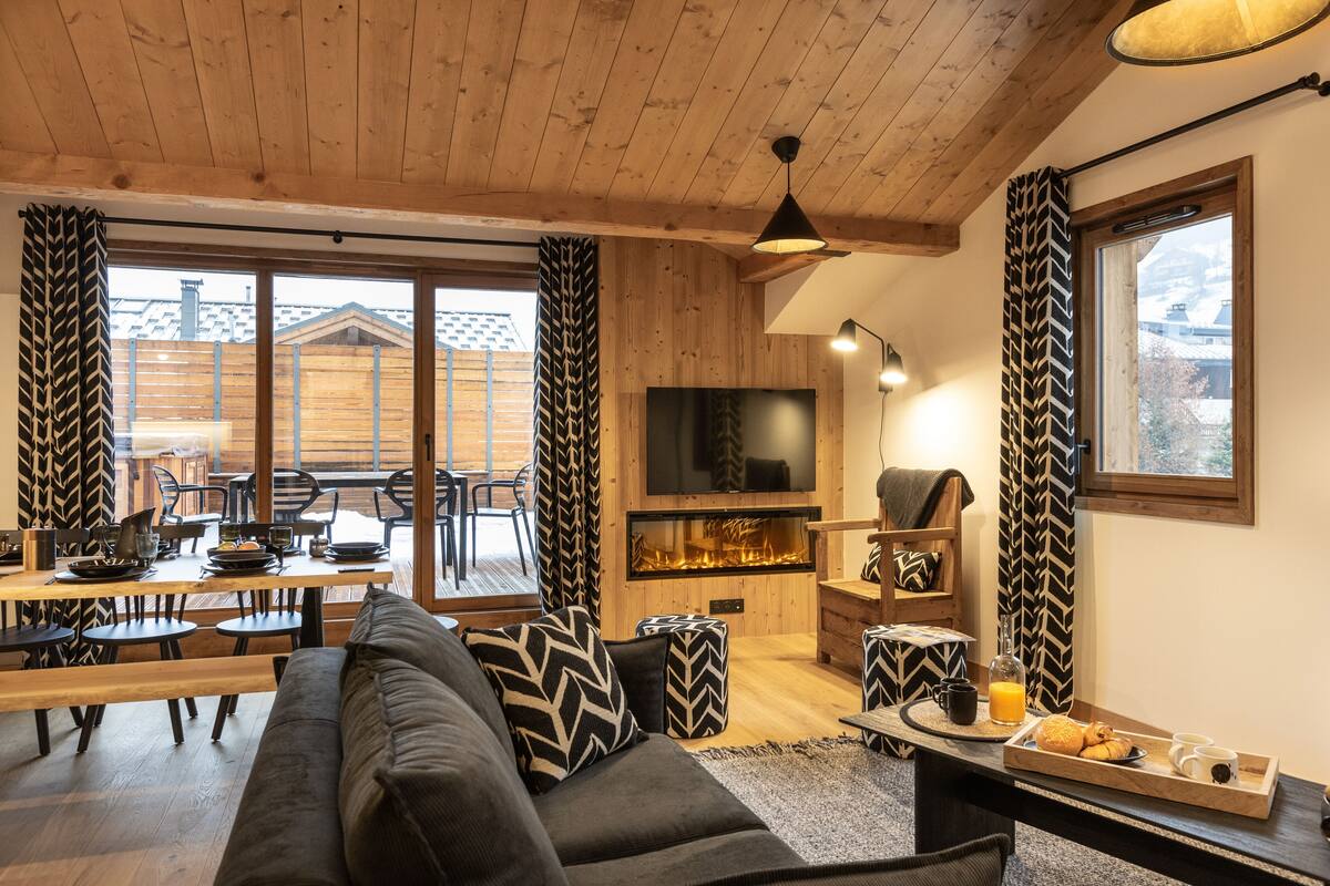 Ein gemütlicher Wohnbereich mit Sofa, Fernseher, Kamin und Esstisch mit Stühlen.