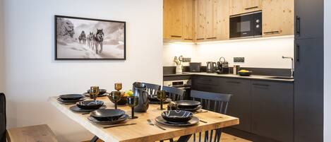 A modern kitchen with wooden cabinets, a microwave, and a dining area with a wooden table set for four.
