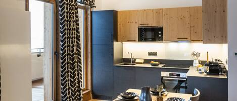 Una cocina moderna con armarios de madera, una mesa de comedor preparada para seis comensales y vistas del área de estar contigua.