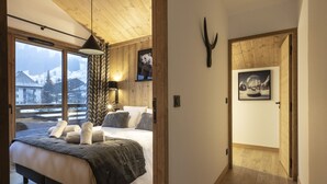 Une chambre à coucher avec un lit, une grande fenêtre, un plafond en bois et une porte donnant sur une autre pièce.